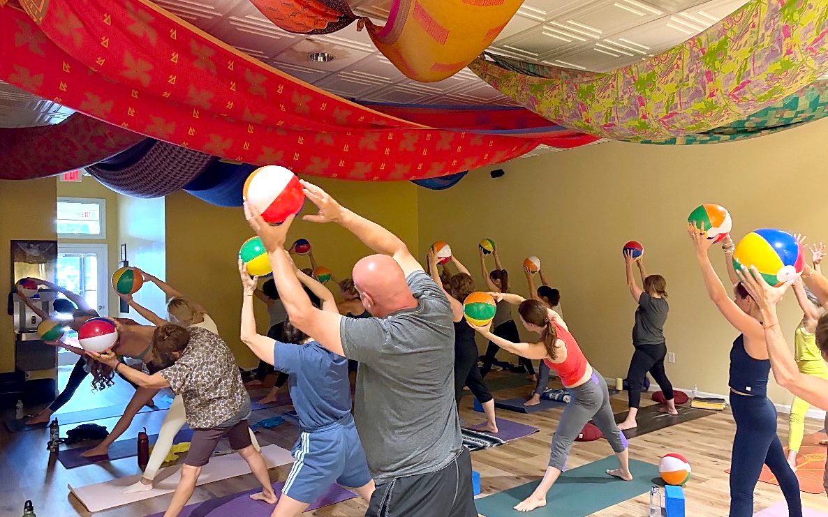 A class reaching up with beach balls under the fabric ceiling